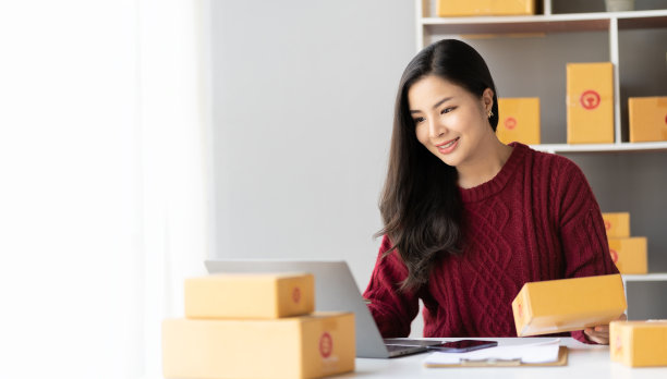 女企业主拿着包裹箱，在家办公室用智能手机在线销售。中小企业经营者图片下载