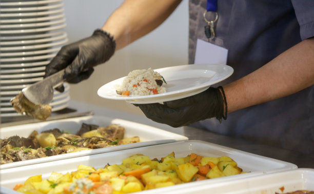 自助餐式服务——食堂工作人员在上菜线上把食物放在盘子里图片下载