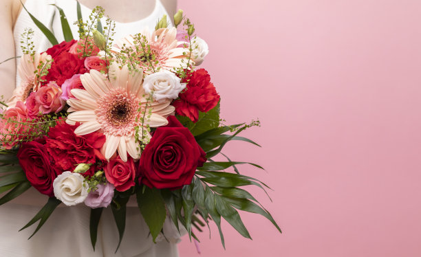 模特新娘，身穿白色婚纱的短身女子手持混合鲜花，粉色背景上的花束。文本复制空间图片下载