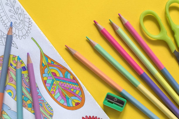 抗压力着色书和粉彩两面铅笔在一个黄色的背景。艺术治疗。图片下载