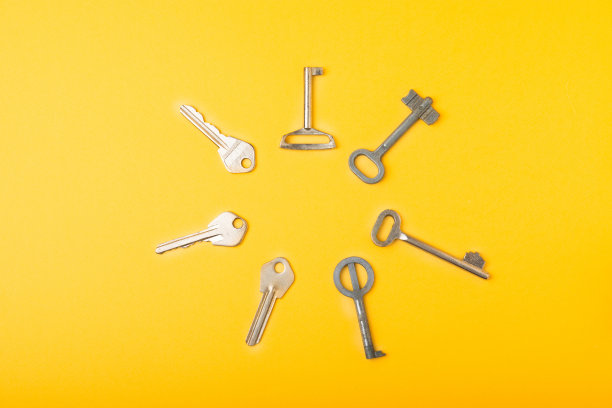 带钥匙链的房子形状的钥匙。黄色背景的构图。设计元素。房地产和保险概念。副本的空间。图片下载