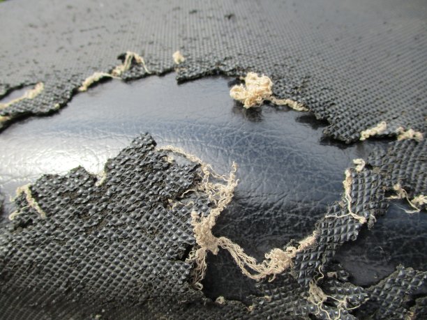 旧黑色皮革摩托车座椅损坏和破碎的特写照片图片下载