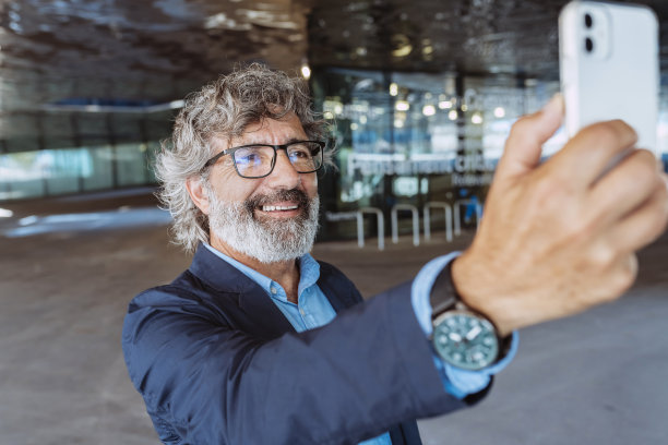 兴高采烈的资深商人用智能手机自拍图片下载