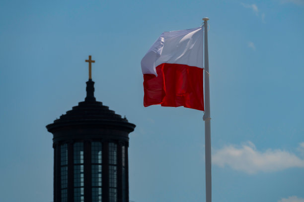 华沙圣三一教堂的十字架上，迎风飘扬的波兰国旗图片下载