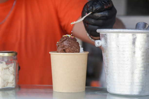 冰淇淋店的工作人员在冰淇淋上撒糖屑图片下载