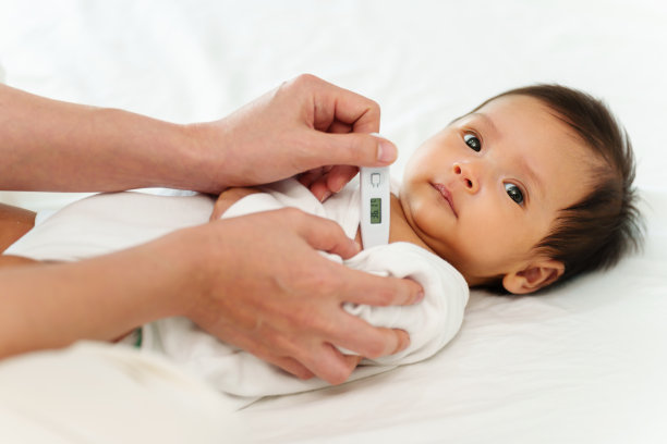 母亲在生病婴儿的腋下测量体温。生病的孩子在床上发高烧图片下载