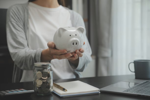 女人用手把钱硬币放进猪里，是为了省钱、财富和理财的观念。图片下载