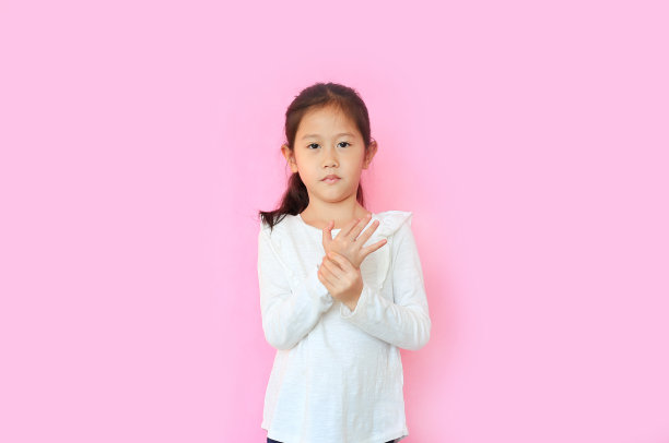 肖像小亚洲儿童女孩痛苦的手和手指孤立在粉红色的背景。不快乐的孩子用表情触摸着痛苦的手势。图片下载