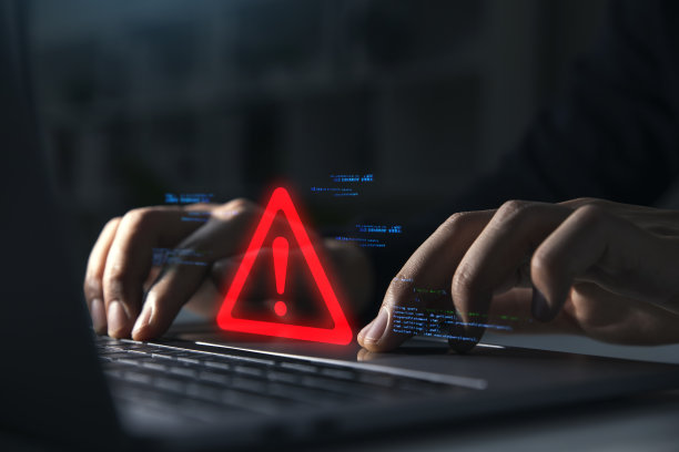 商人使用笔记本电脑的手，上面有警告标志图片下载