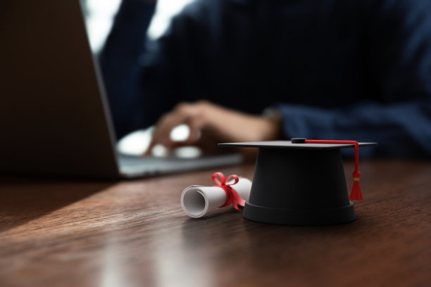 学位帽和文凭证书放在商人面前的桌子上图片下载