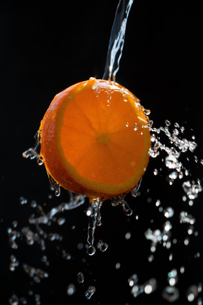 将一片橙子浸入大量的水中，背景色为黑色图片下载