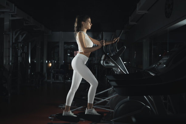 一位年轻的职业教练正在一家健身工作室从事步进模拟器的工作。在体育课上训练的漂亮女孩。晚上锻炼。运动与健康。积极的生活方式图片下载