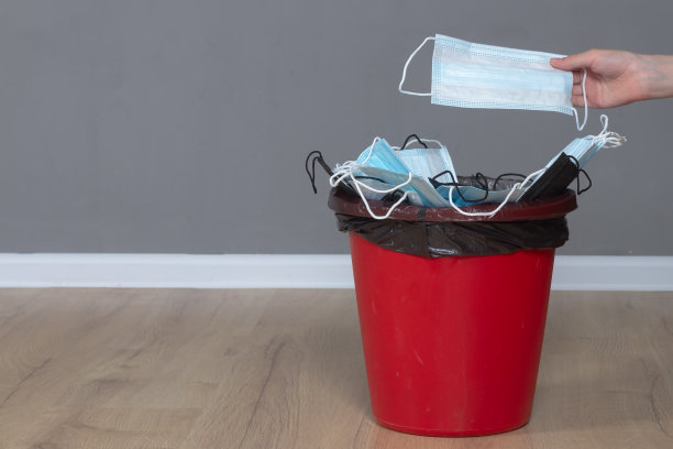 在冠状病毒大流行结束后，将新的医用防护口罩扔进垃圾桶图片下载