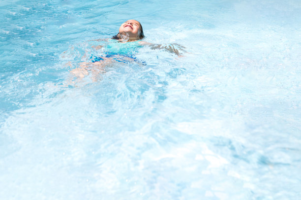 黑头发的女孩，在一个游泳池里，放松地躺在水里。泳池、游泳、泳装、儿童、夏日、休闲、度假、度假、旅游等概念。图片下载