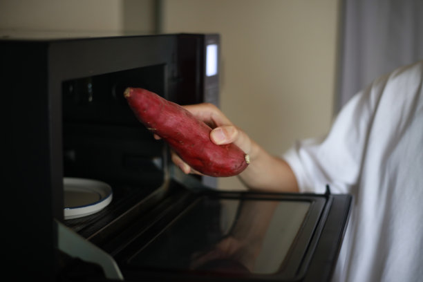 一个人正在用微波炉加热红薯图片下载