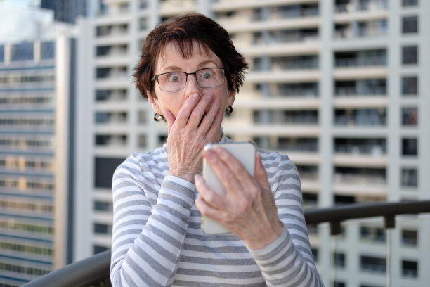 年长的女人从手机上抬头，表情震惊图片下载