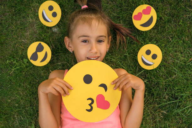 漂亮的十几岁的女孩手里拿着一个表情符号，发送一个飞吻图片下载