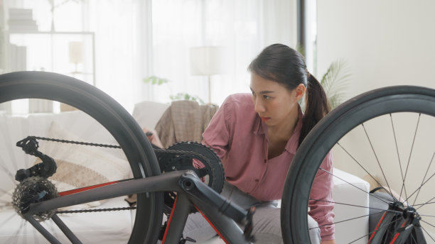 年轻的亚洲女子在家里用快乐的方式保养自行车。业务通勤。图片下载