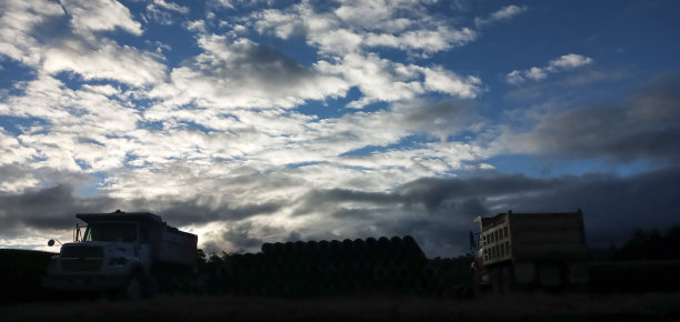 户外建筑卡车的剪影，日落，蓝色的天空和大量的云。图片下载