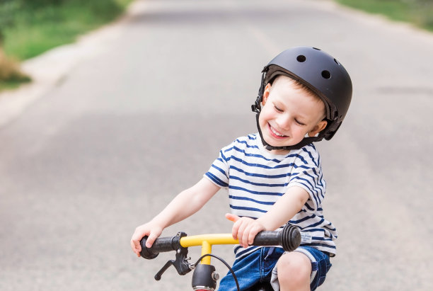 一个快乐的小男孩戴着头盔在户外骑着跑步自行车。一个快乐的孩子正在从事一项积极的运动。保护。人寿保险和儿童安全。图片下载