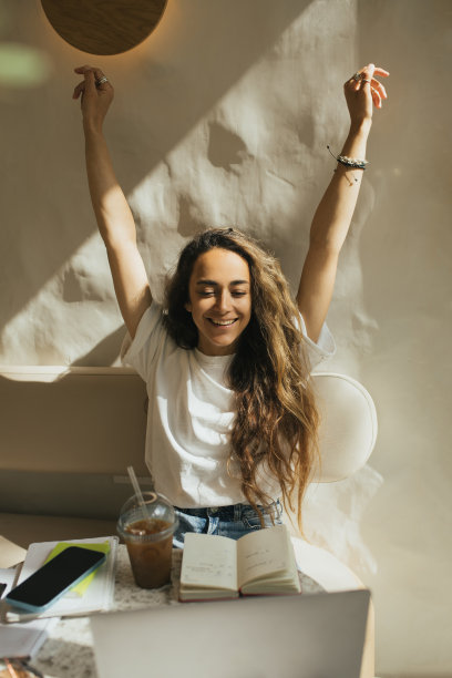 在咖啡馆工作的年轻自由职业者，使用她的笔记本电脑和智能手机。图片下载