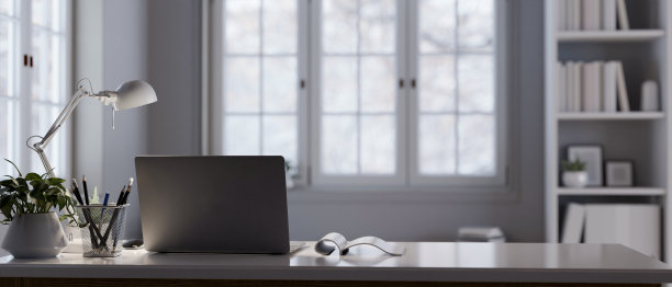 一个现代化的家庭办公室，有笔记本电脑、文具、台灯和桌子上的装饰品。图片下载