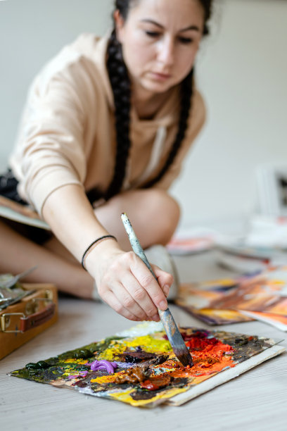 才华横溢的女艺术家在她的艺术工作室的地板上画画。创造性的工作氛围图片下载