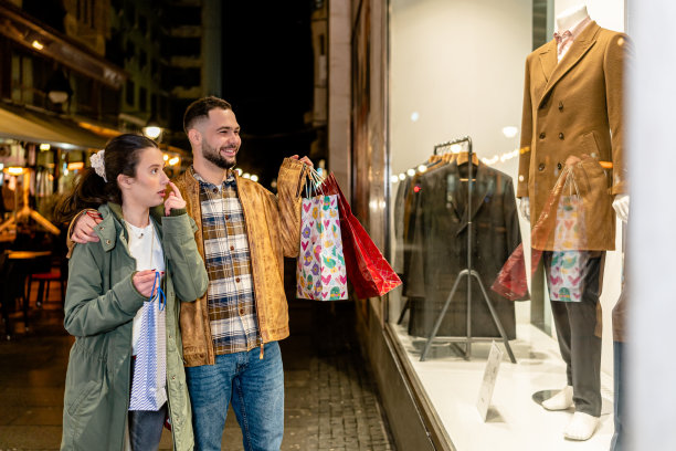 浪漫的夫妇漫步在城市的街道和欣赏精品橱窗展示图片下载