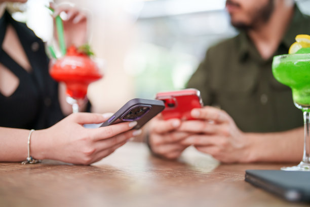 朋友们在酒吧喝着鸡尾酒玩手机。图片下载