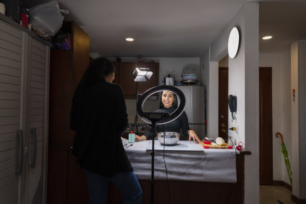 一位来自拉丁美洲的YouTube女主播在助手的帮助下，在家里的厨房里为她的YouTube粉丝录制了一段食谱视频图片下载