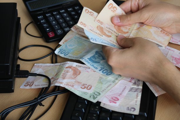 一个人在用手数土耳其钞票。计算器在后台。关于税收和加息的新闻。提高，税收，最低工资图片下载