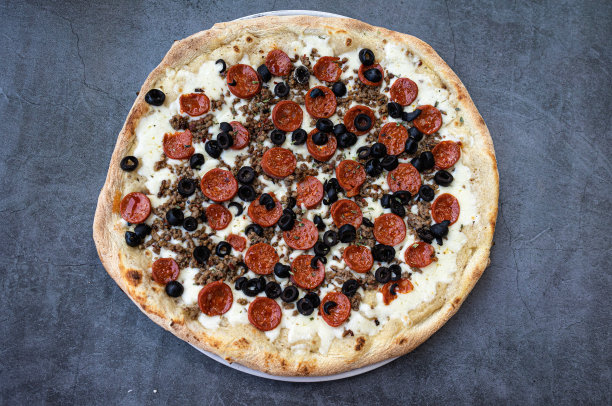 美味的意大利辣香肠披萨配白辣酱和牛肉，质朴的餐桌。前视图。图片下载