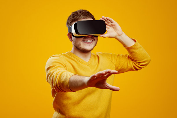 穿着黄色毛衣的年轻人戴着vr耳机观看，触摸着漂浮的虚拟屏幕图片下载