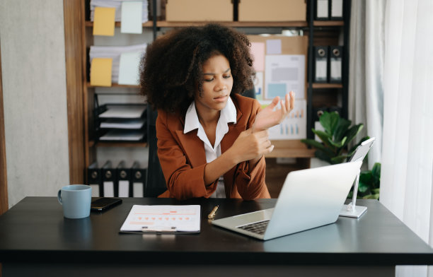 劳累过度的年轻非洲女上班族在办公桌前工作了一整天后颈部疼痛。图片下载
