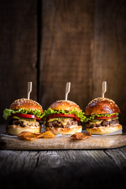 美味的芝士汉堡，有生菜、切达奶酪、西红柿和泡菜。汉堡面包加芝麻。乡村的气氛。美味的快餐。图片下载