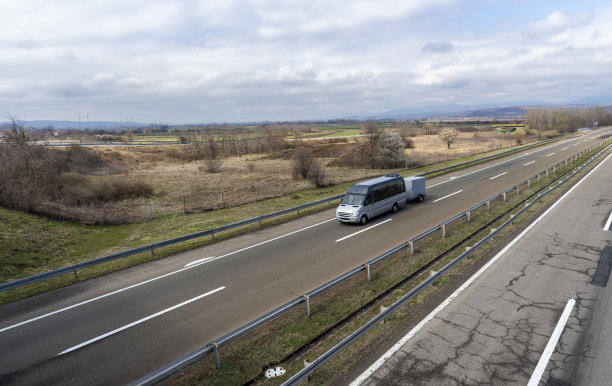 一辆现代的灰色小巴正在行驶，上面挂着拖车，用来在高速公路上运输东西。图片下载