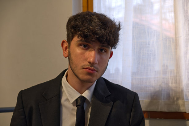 一个穿着西装坐着的白人少年在整理他的白衬衫图片下载