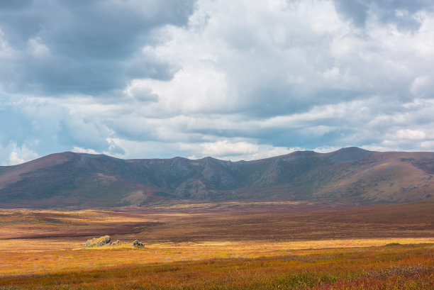 五彩缤纷的秋景，阳光明媚的高山高原和山脉在戏剧性的天空下。鲜艳的秋色笼罩着群山。多变天气里的阳光和云影。晴天雨天图片下载