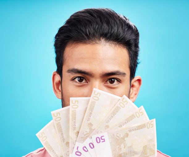 人像男子，手持纸币，蓝色背景。金融储蓄、奖金或竞赛获胜，在工作室获得经济成功的男性图片下载