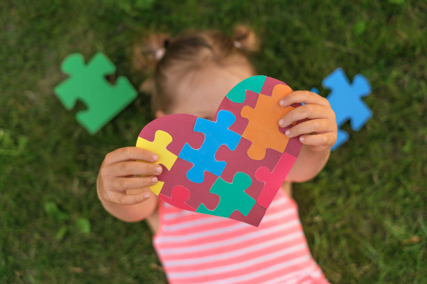 躺在草地上的女孩手里拿着一颗粉红色的大心，里面有拼图图片下载