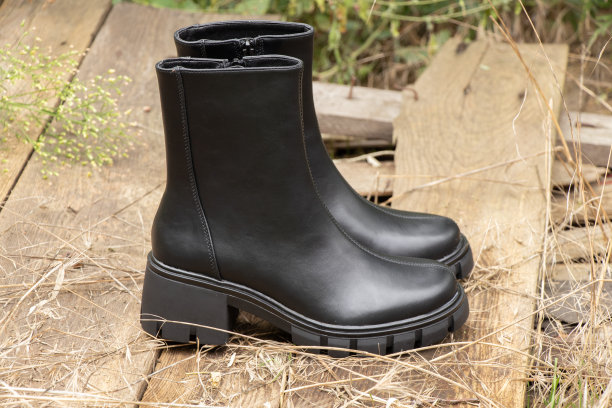 黑色厚底女式高筒靴立在街上的旧木板上，是女式冬鞋图片下载