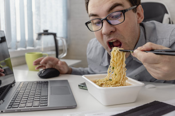 在办公室用笔记本电脑工作时吃泡面图片下载