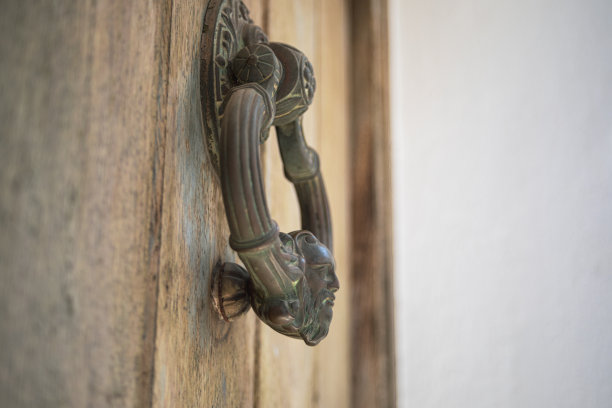 一扇旧木门的大型金属青铜圆形门环的特写细节图片下载