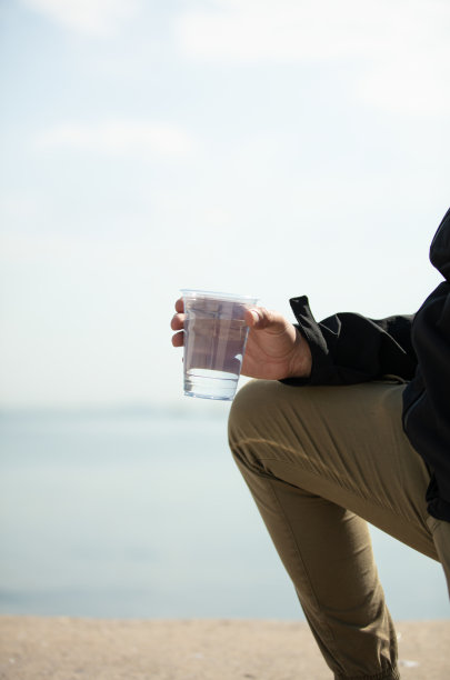 年轻人拿着一个塑料杯。图片下载