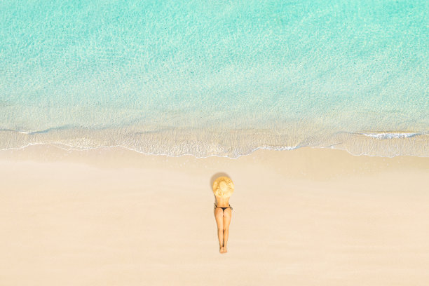 俯视图的女人在比基尼和草帽躺和日光浴的热带塞舌尔海滩。航拍、无人机视图图片下载