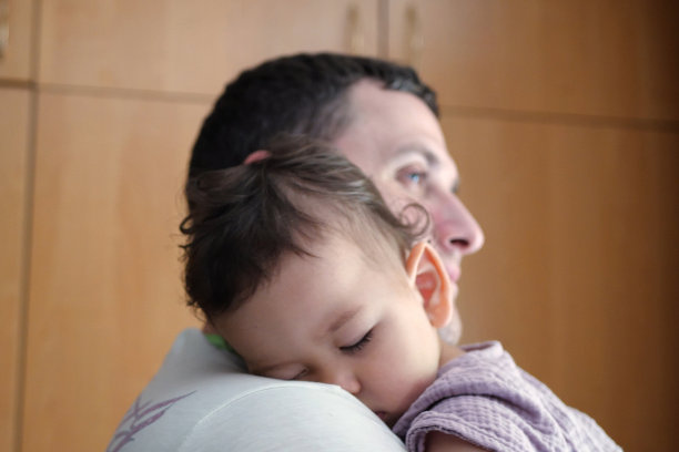 可爱的新生儿睡在父亲的怀里。一位慈爱的父亲在家里抱着她刚出生的孩子。一位快乐的母亲抱着熟睡的婴儿的画像图片下载