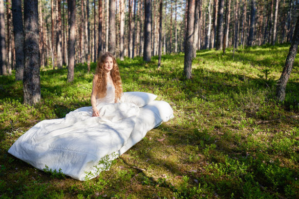 夏天的森林里，一个女人睡在床垫上图片下载