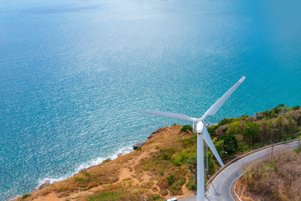 风力涡轮机在山和蓝色的海洋背景与文本的复制空间。图片下载