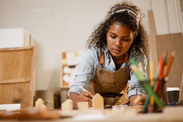 非洲黑人妇女在木材工作室车间用木板设计家居家具。图片下载