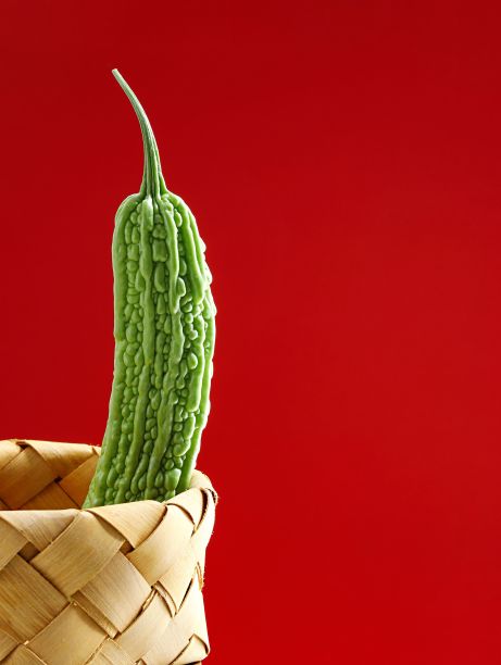 三个成熟的绿色苦瓜在红色背景的柳条篮子里的特写图像图片下载